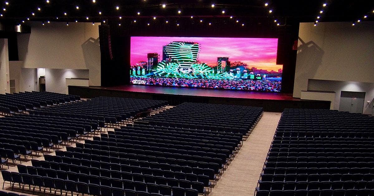 Wide indoor LED video wall behind a stage in an auditorium